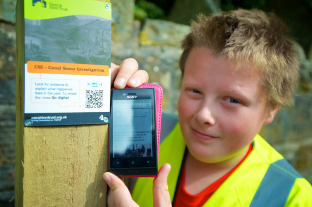 boy with next next to qr code trail plaque